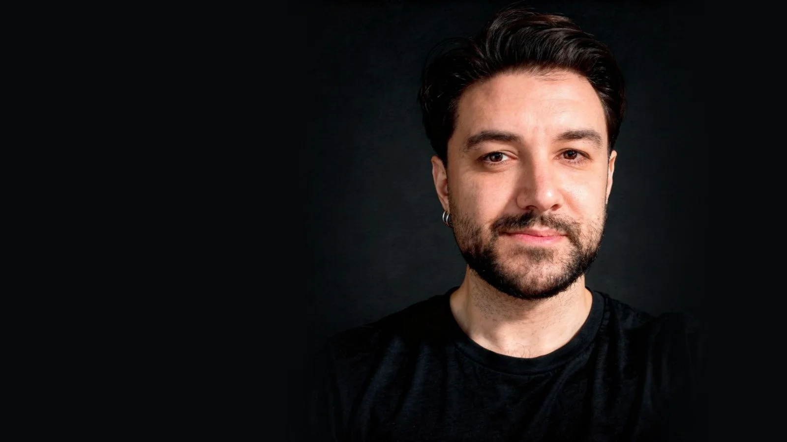 Portrait of Alptekin Canatar in a black T-shirt against a dark background.