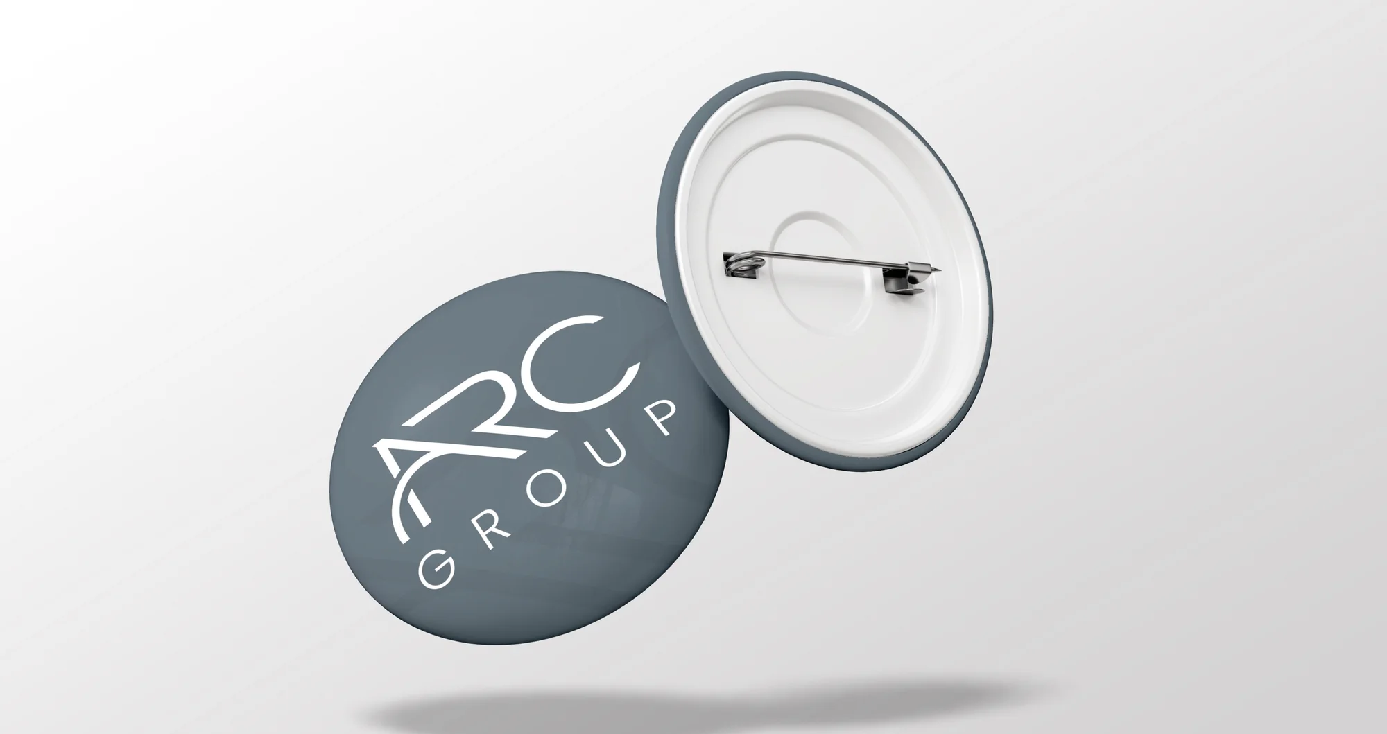 A pin badge with a white logo on A Gray, shown with its back.