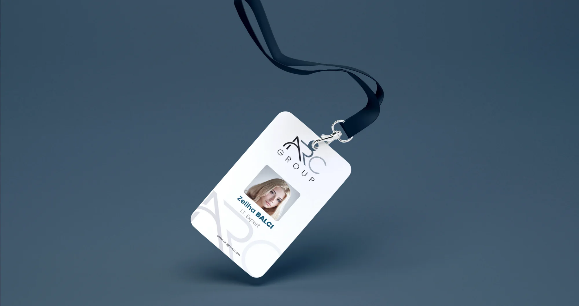 A white staff ID card on a lanyard against blue-grey, with logo and photo area.