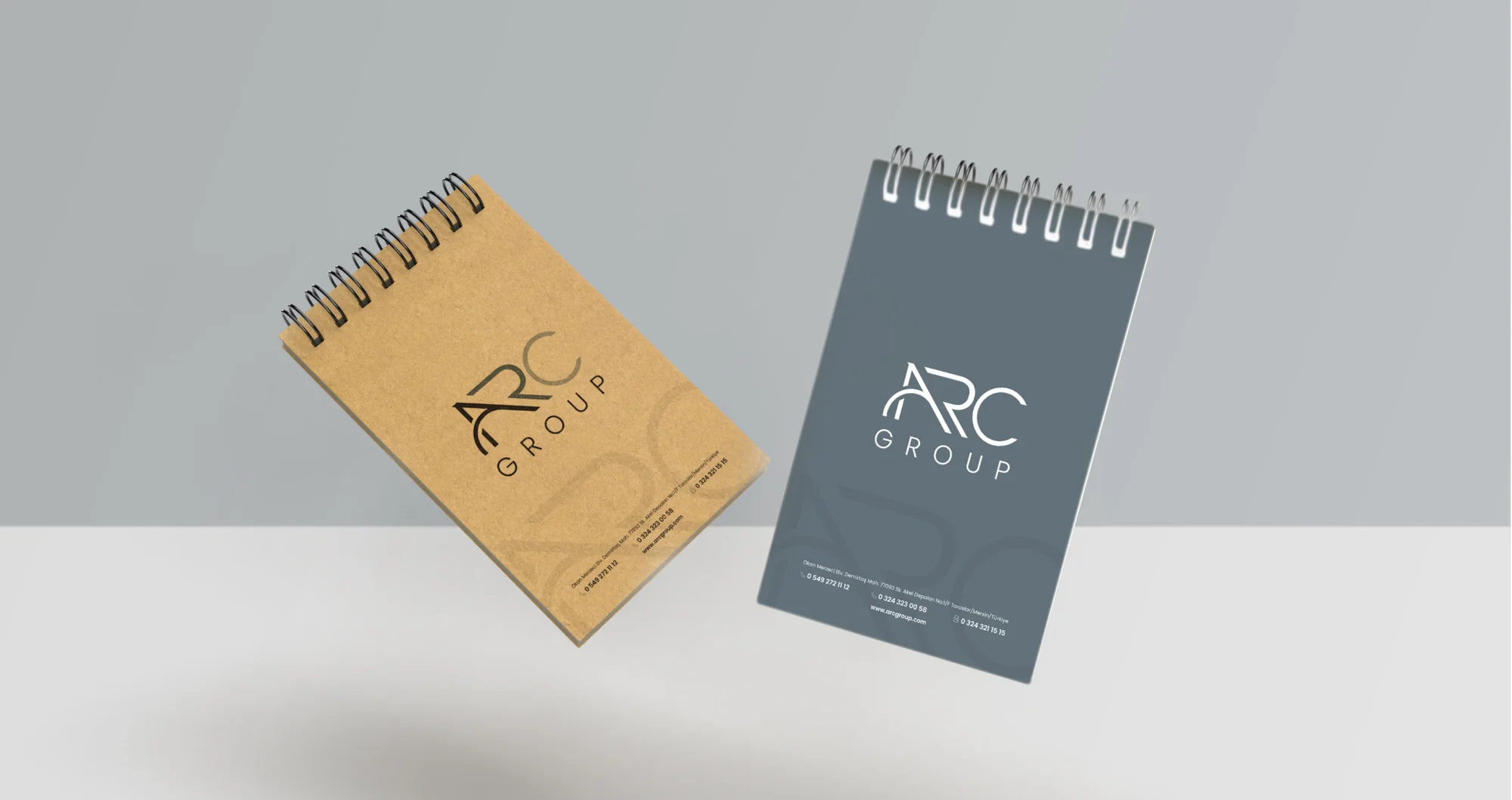 Two floating spiral notepads, one in kraft paper, one with an A Gray cover.