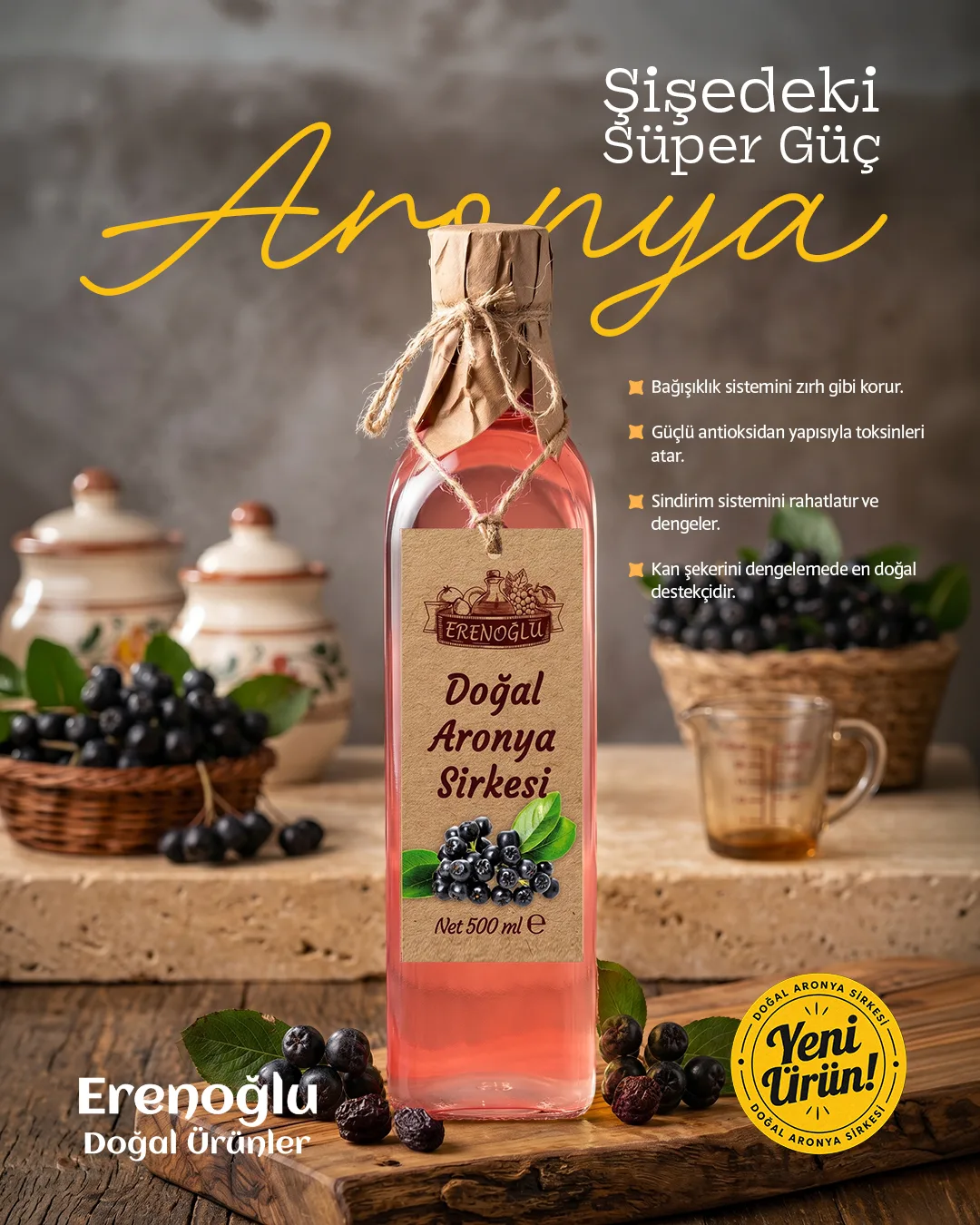 A pink bottle of aronia vinegar among aronia berries and baskets; a yellow script "Aronya" and a "New Product" badge.