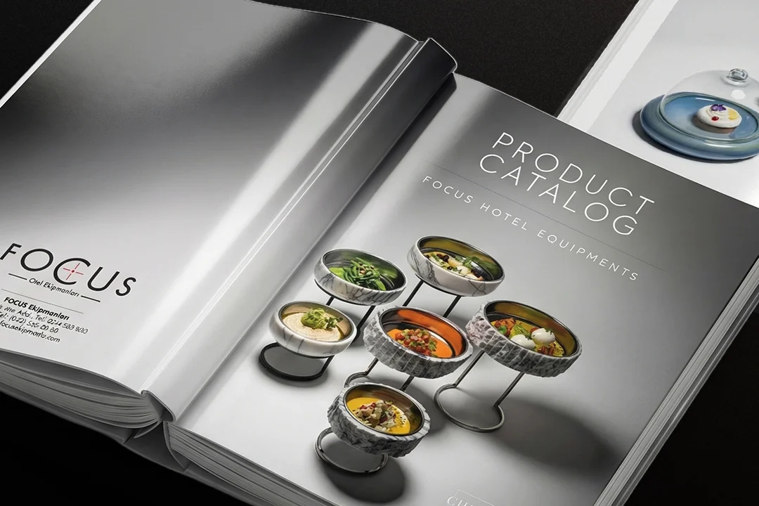 Açık duran Focus kataloğu: gri degrade kapakta PRODUCT CATALOG yazısı ve metal ayaklı mermer kâselerde sunulan yemekler.