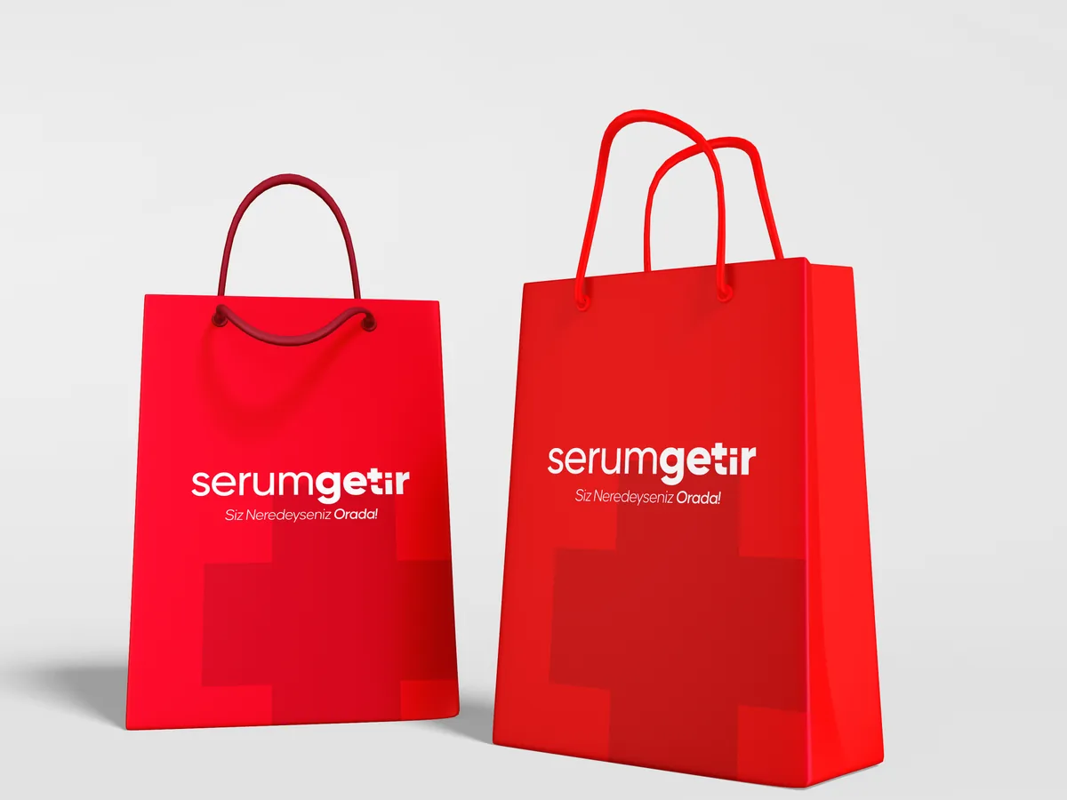 Two red paper bags with a white logo and a large, faint cross motif.
