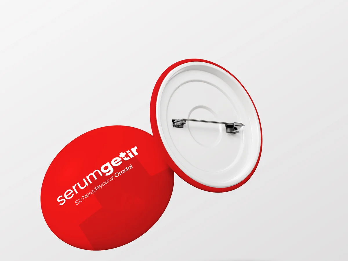 A red pin badge with the logo, shown front and back on a light ground.